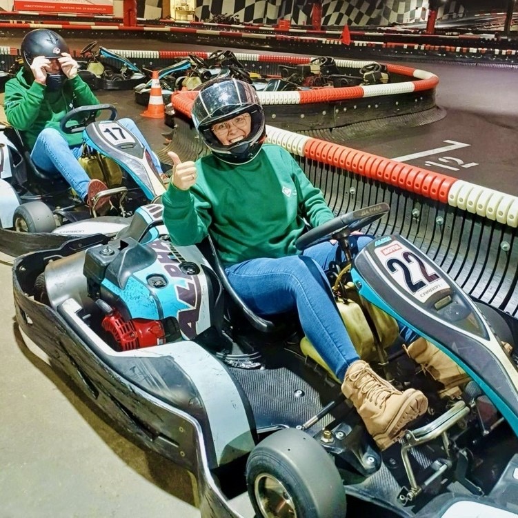 Twee medewerkers van Castelein Outdoor op de kartbaan, gekleed in bedrijfsuniform.