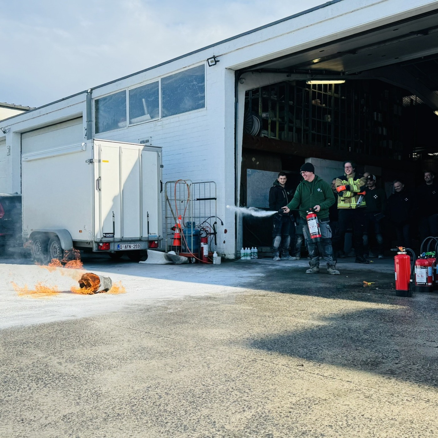 Leden van Castelein Outdoor met brandblusapparaten tijdens een training op het bedrijfsterrein.