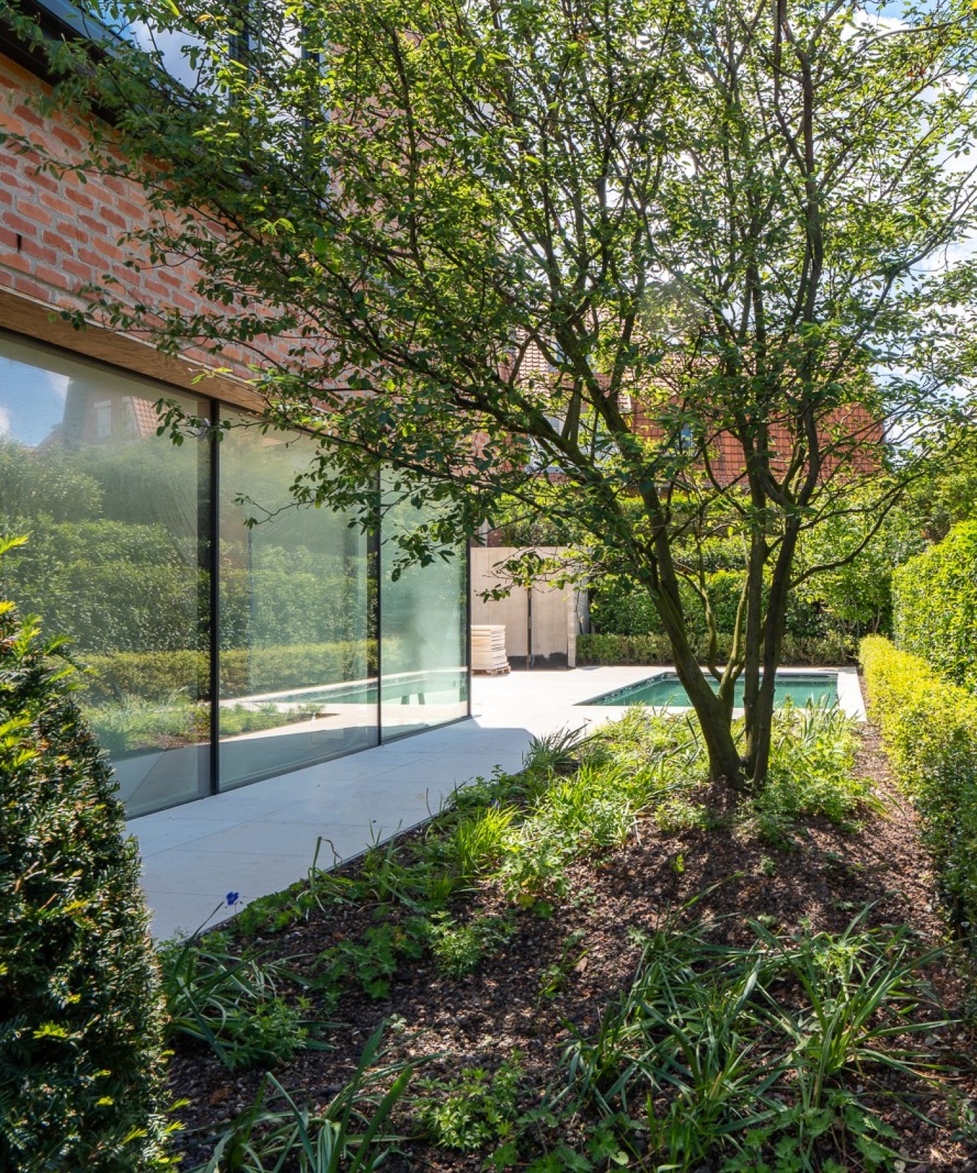 Aangelegde tuin in Knokke met gesnoeide hagen en zwembad, aansluitend op een tijdloze villa aan de kust.