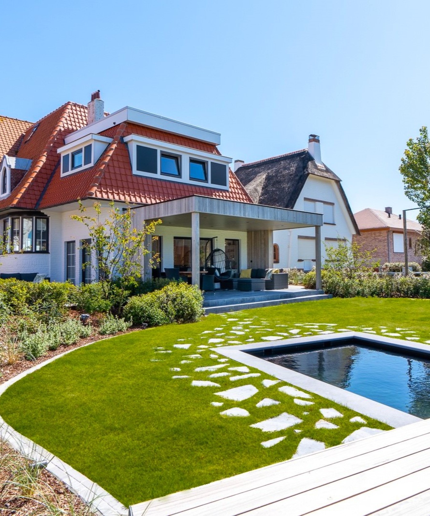 Tuin met waterpartij, stapstenen, zonneterras en overdekt terras bij een charmante kustvilla.