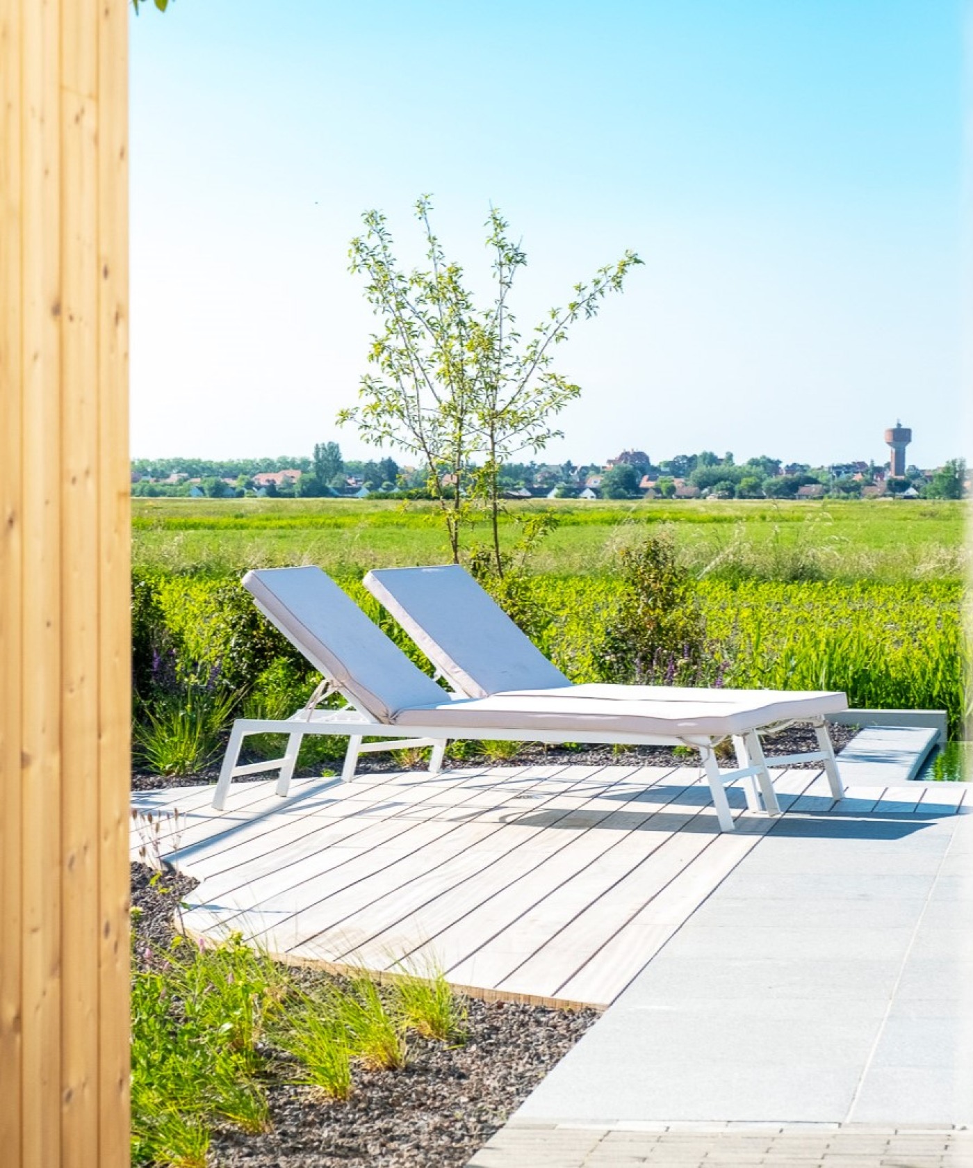 Loungestoelen op houten zonneterras met infinity-pool en panoramisch uitzicht.