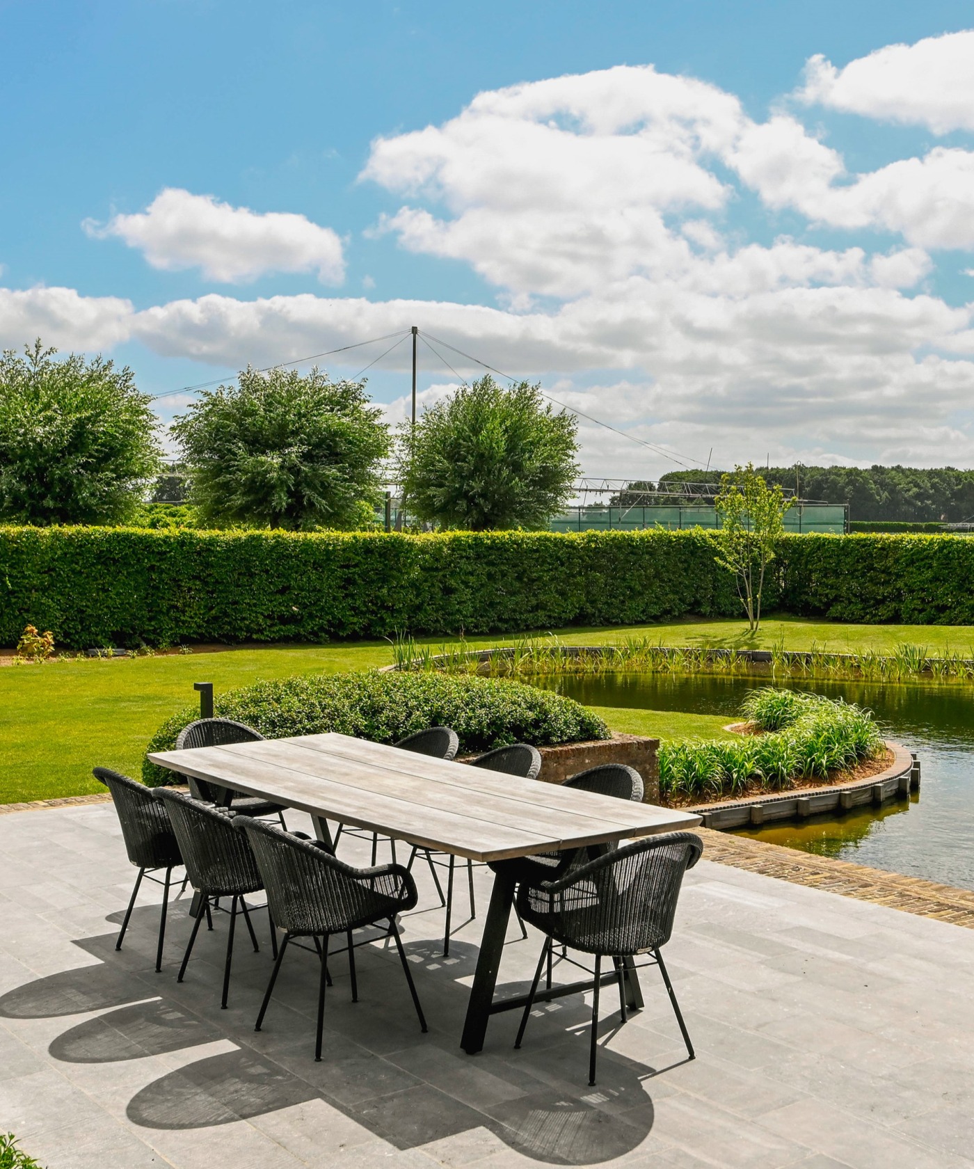 Terras aan natuurlijke zwemvijver met uitzicht op de gerenoveerde groene tuin in Jabbeke.