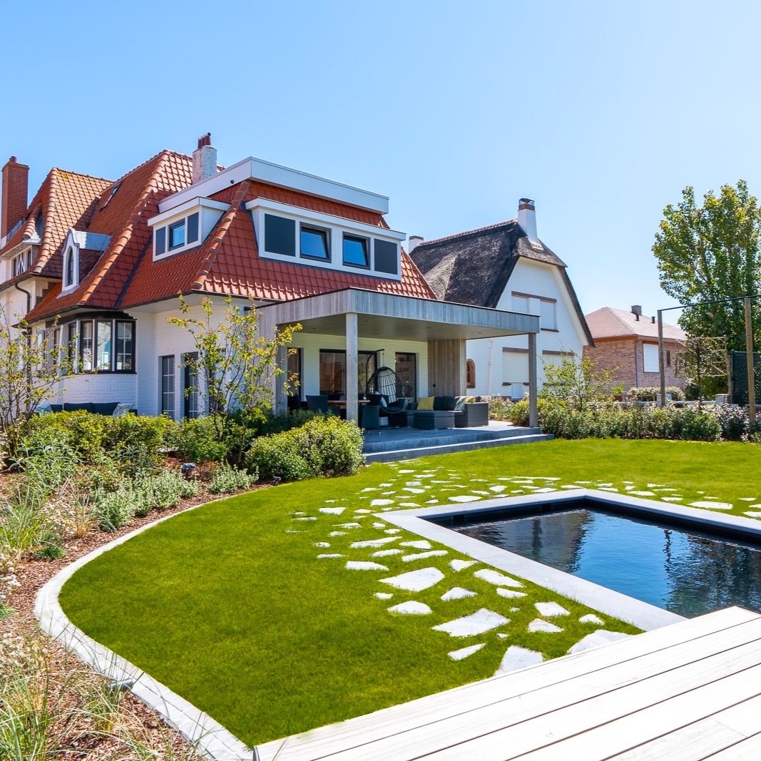Tuin met waterpartij, stapstenen, zonneterras en overdekt terras bij een charmante kustvilla.