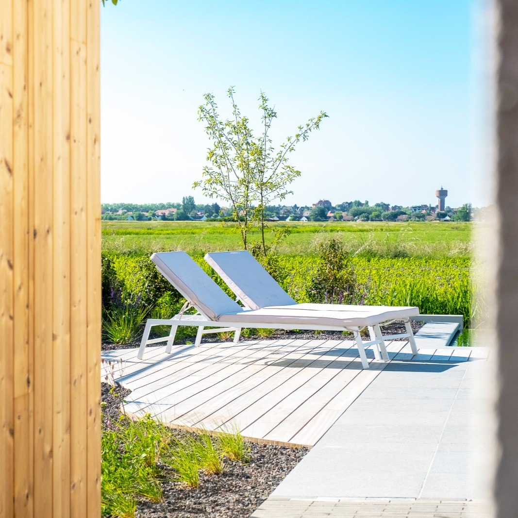 Loungestoelen op houten zonneterras met infinity-pool en panoramisch uitzicht.