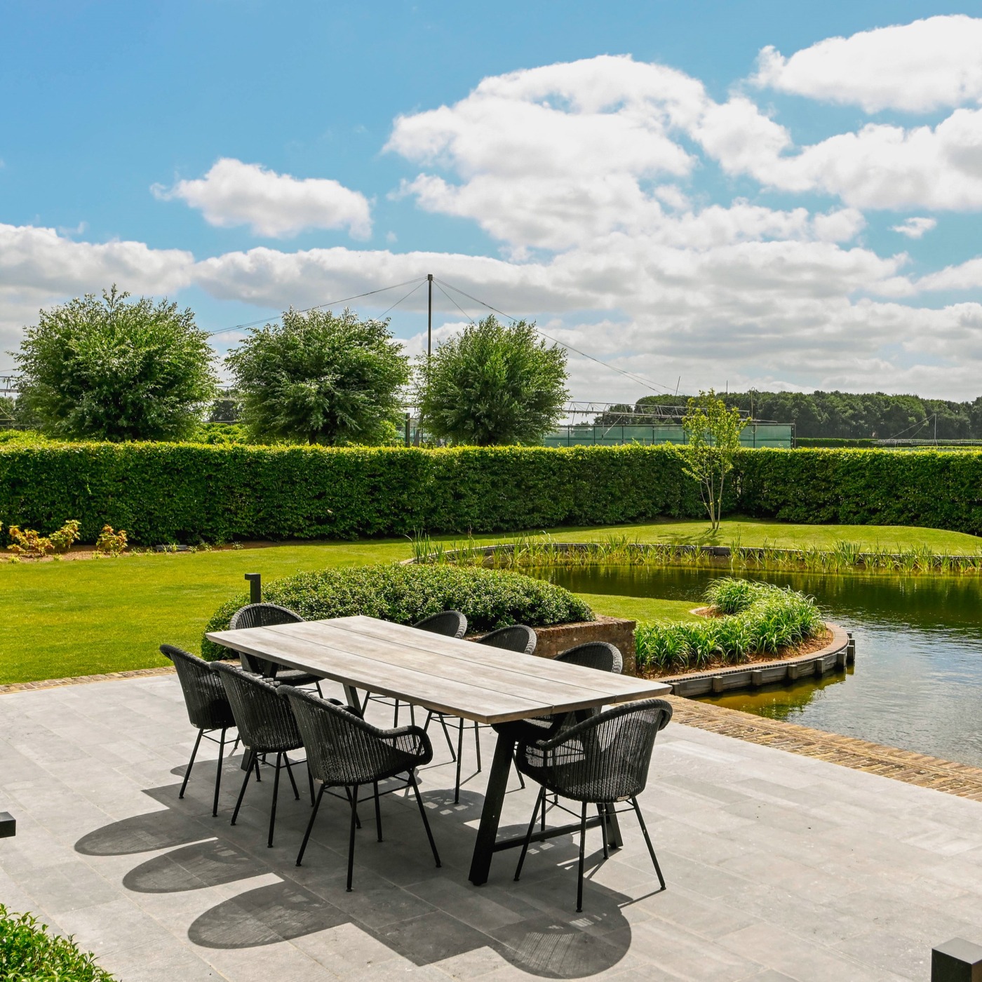 Terras aan natuurlijke zwemvijver met uitzicht op de gerenoveerde groene tuin in Jabbeke.